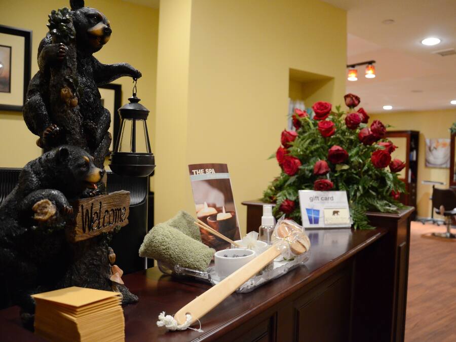 A reception desk with a welcome sign, a vase of red roses, a gift card, and a wooden spoon.