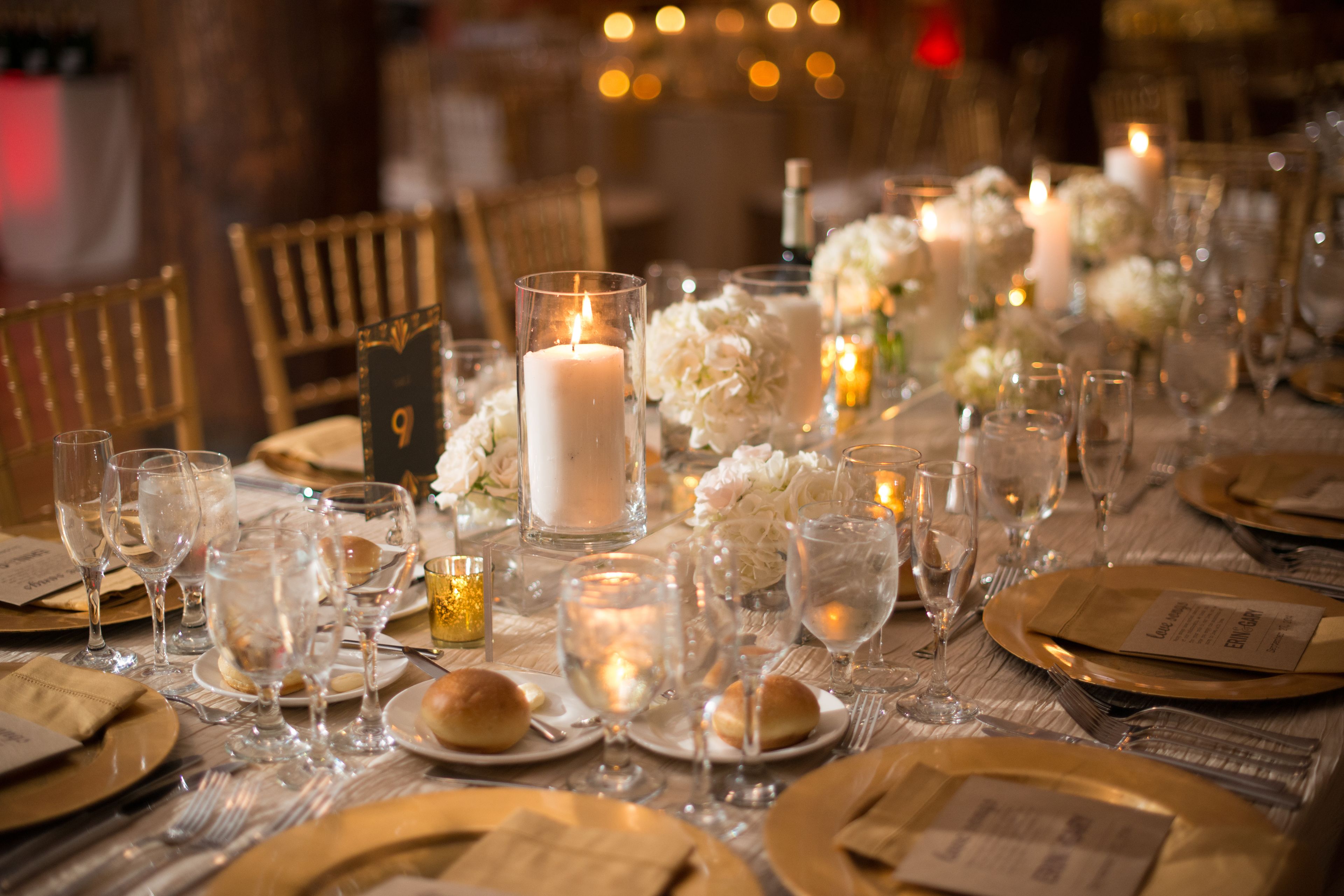 Una mesa dispuesta para un evento formal, con velas, cristalería y arreglos florales.