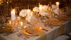 Una mesa dispuesta para un evento formal, con velas, flores y cristalería.