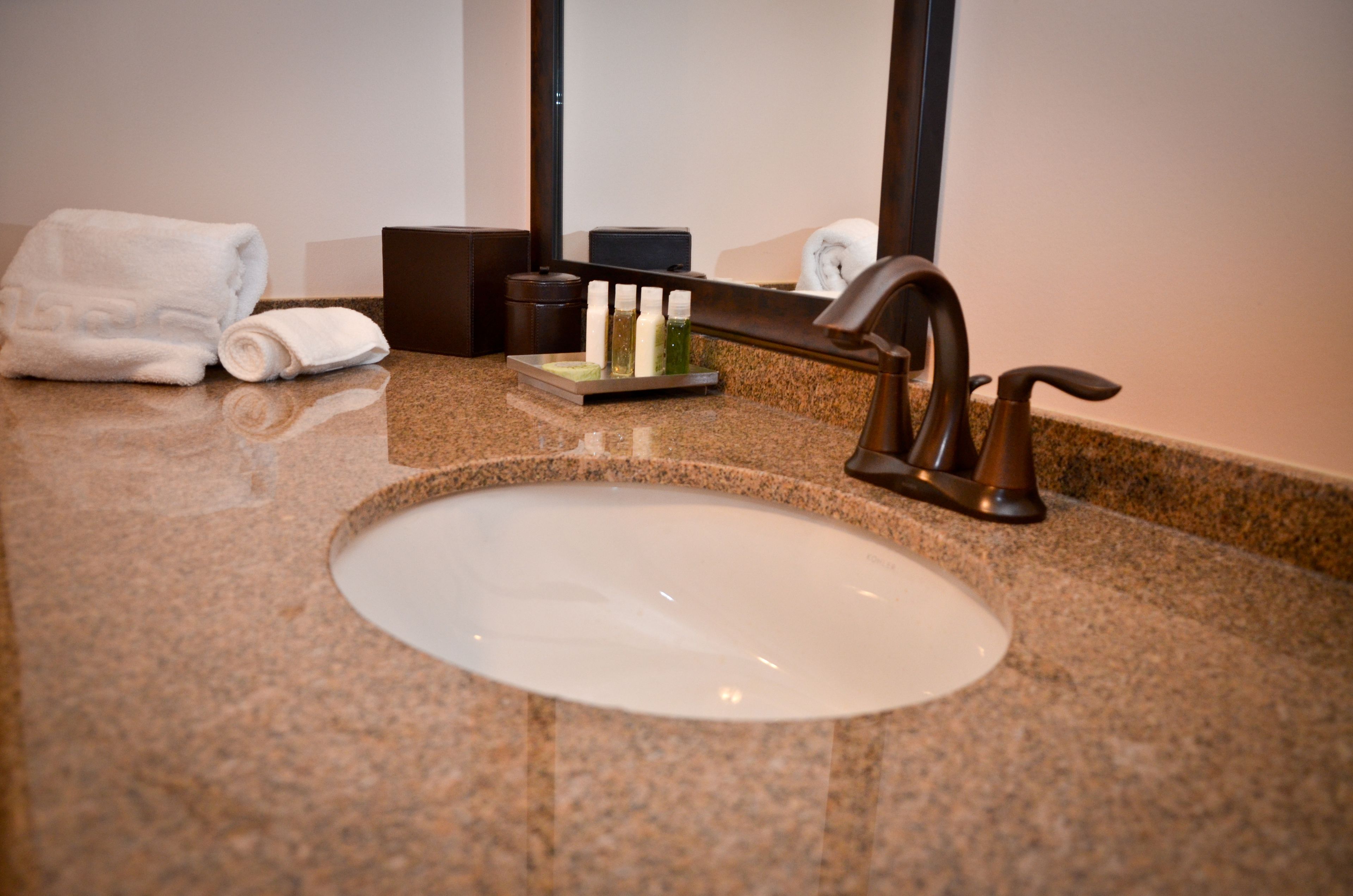 A bathroom sink with a granite countertop, a towel, and toiletries.