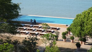 Ein Strand mit Liegestühlen und einem Pool mit Blick auf ein ruhiges Meer.