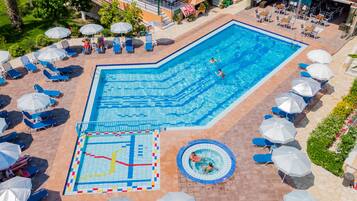 Una piscina al aire libre, sombrillas, sillones reclinables de piscina