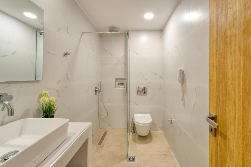 A modern bathroom with a white sink, mirror, and shower.