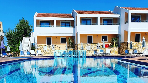 A swimming pool with tiled blue and white patterns, surrounded by lounge chairs and umbrellas. - Oscar Hotel (Zakynthos)