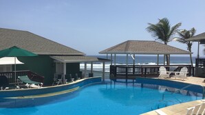 A swimming pool with lounge chairs and umbrellas, overlooking the ocean. - Atlantis Historic Inn (Bathsheba)