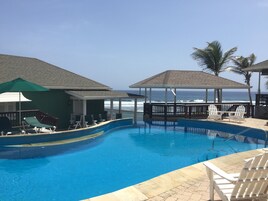 Una piscina con sillones de descanso y sombrillas, con vista al océano.