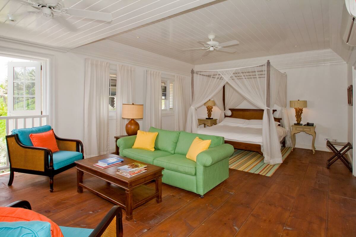 A room with a bed, a green sofa, a wooden coffee table, and a chair.