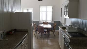 A spacious kitchen with high ceilings, a dining area, and a large window providing natural light.