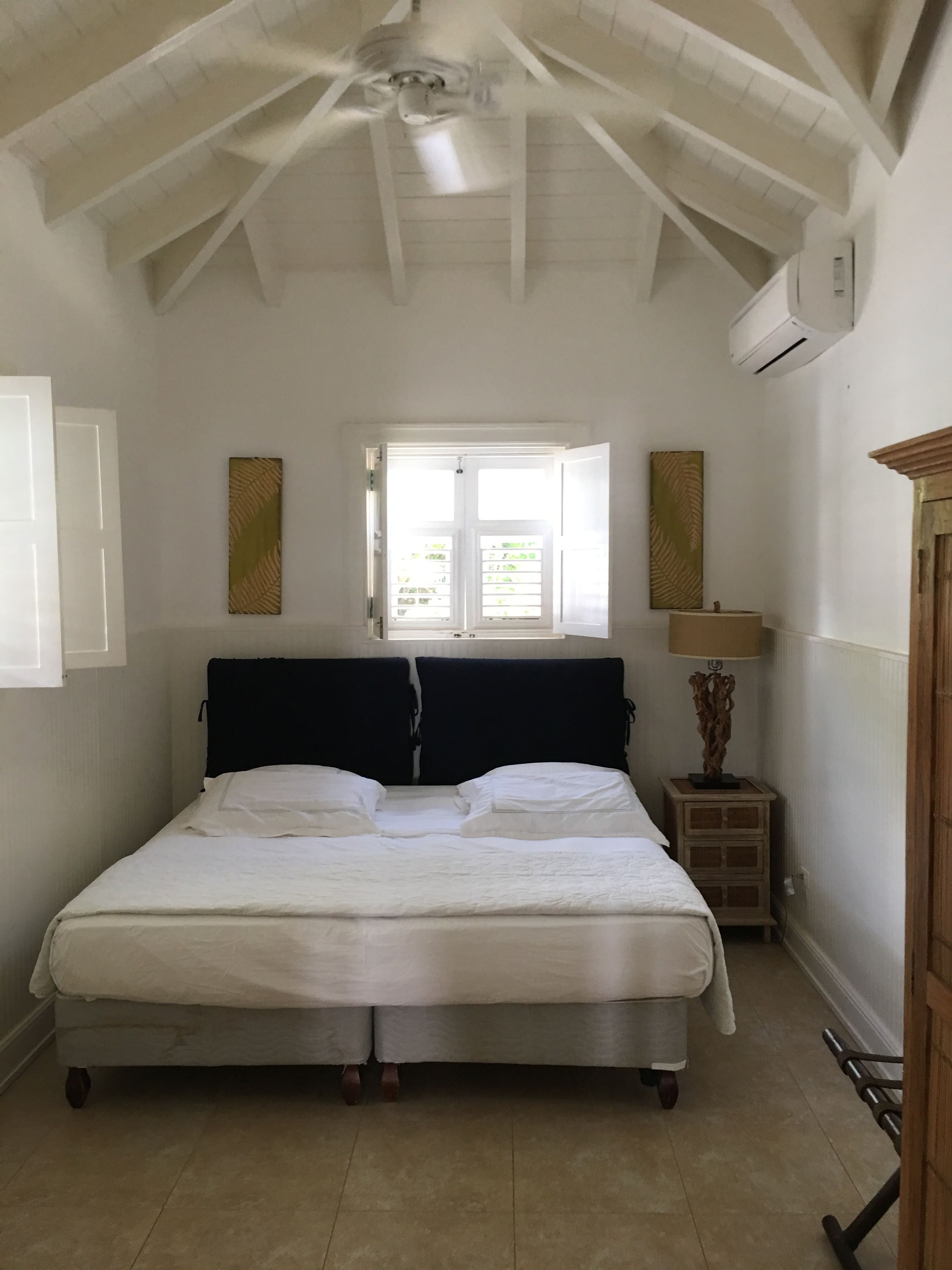Un dormitorio con cama, ventana, mesita de noche y lámpara.