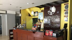 A reception desk with a sign for 'Sampaguita Suites' and a clock displaying the time. - Sampaguita Suites Plaza Garcia (Cebu City)