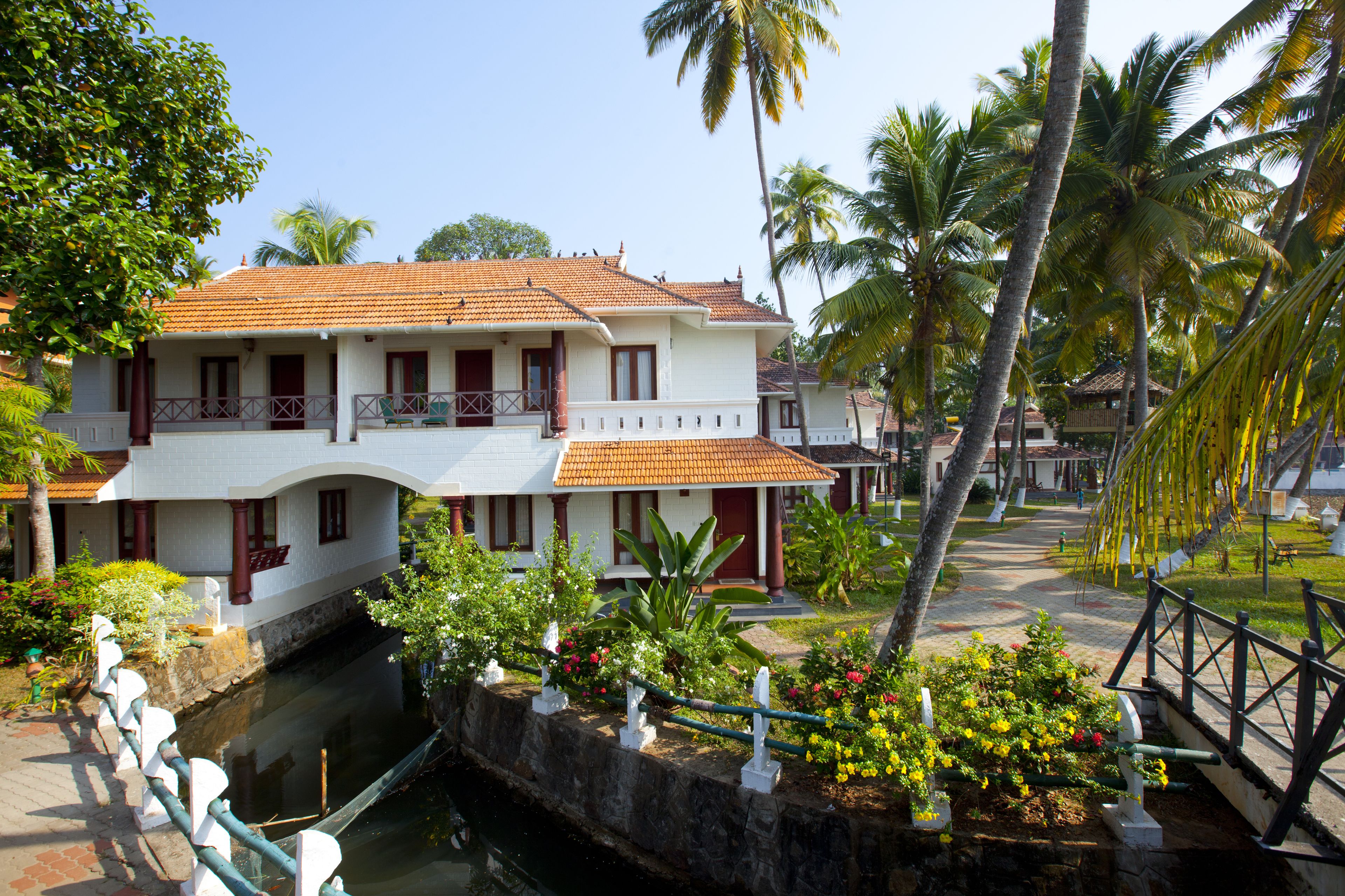 A two-story white building with a tiled roof, a balcony, and a canal in front.