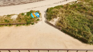 Ein Strand mit einer Holzterrasse und Liegestühlen mit Blick auf den Ozean.