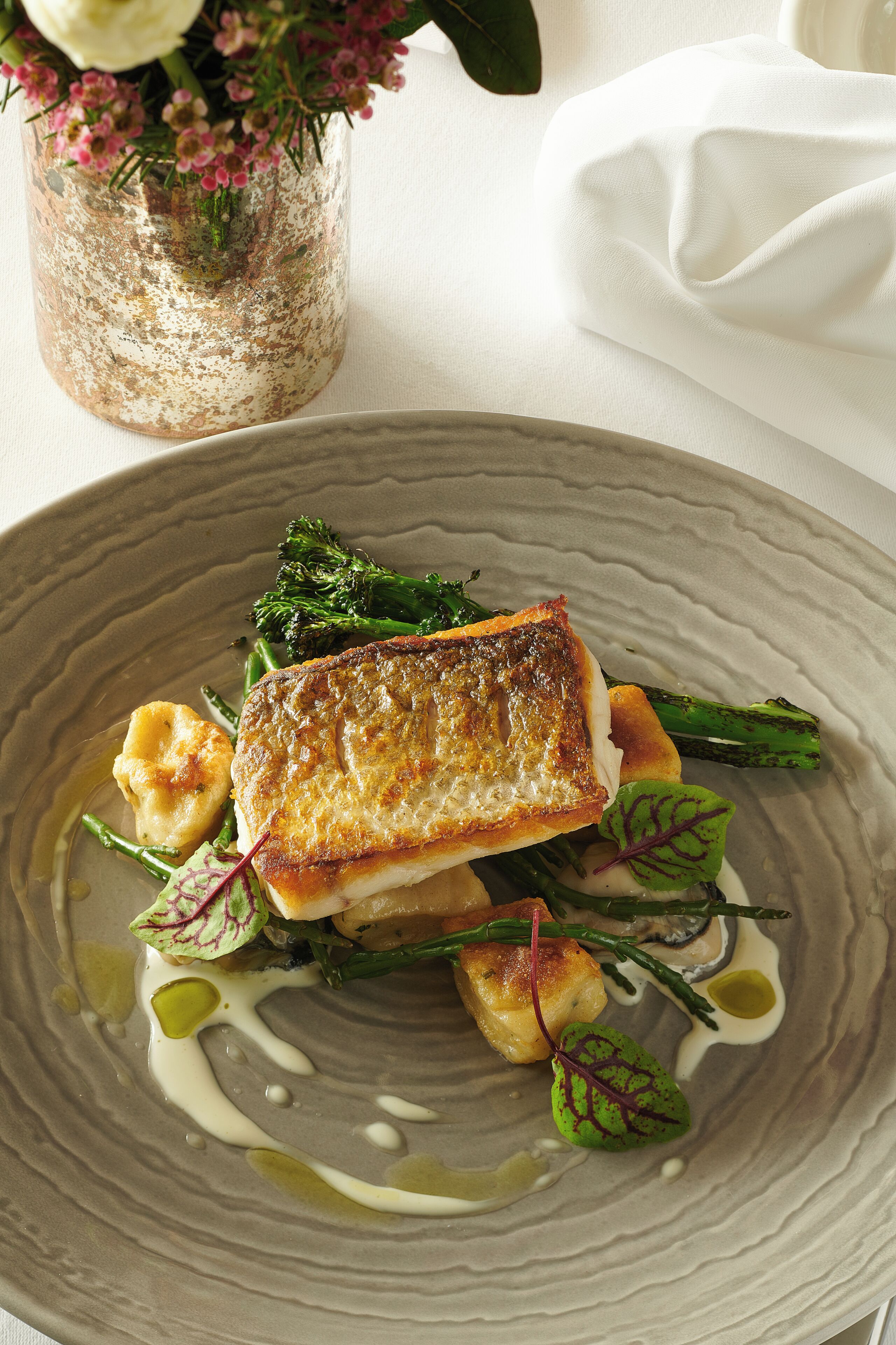 Un plato de comida con pescado, verduras y salsa.
