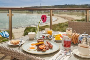 Una mesa de desayuno con diversas opciones de comida y vista al mar.