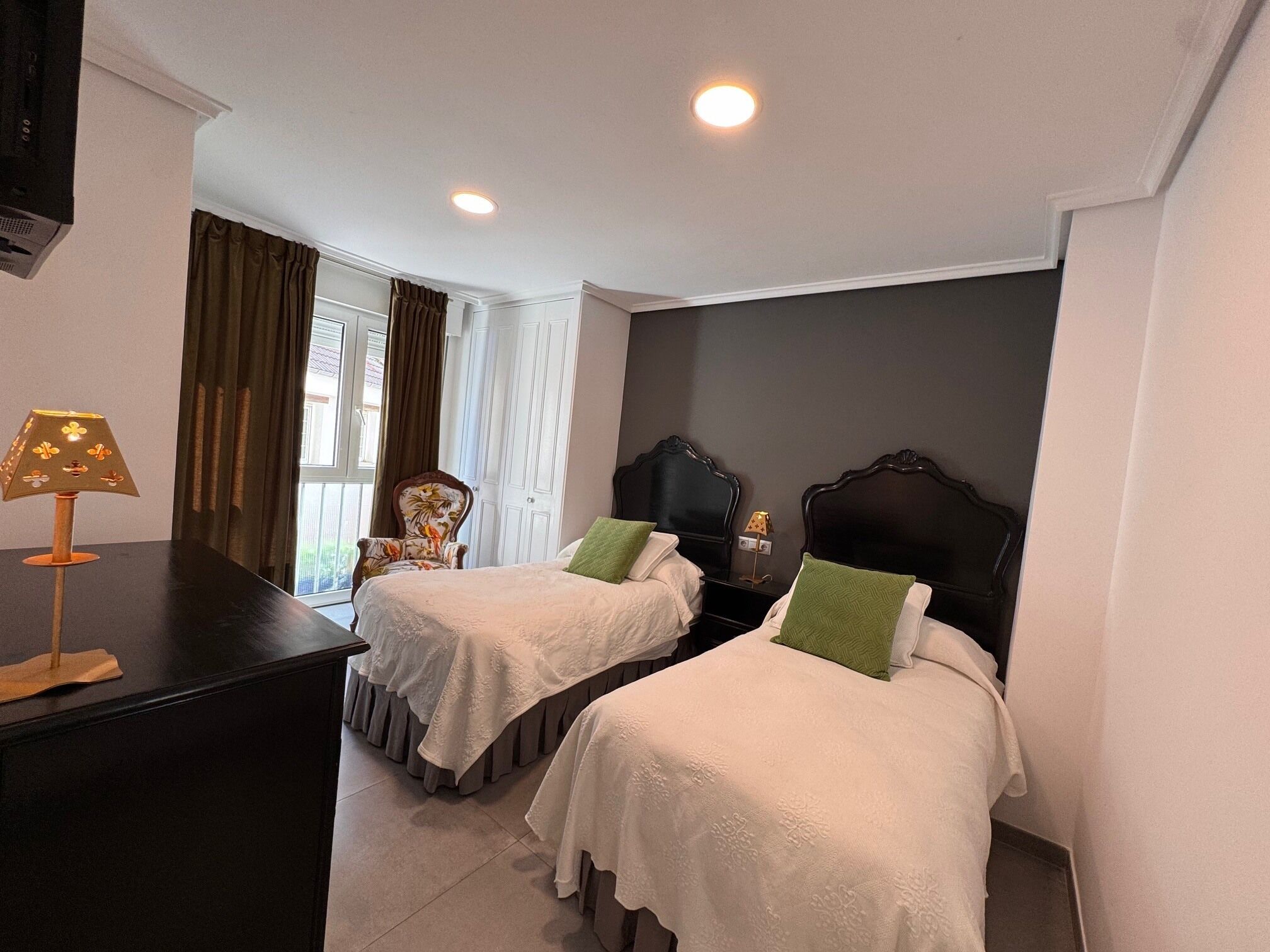 A hotel room with two beds, a desk, a chair, and a window with curtains.