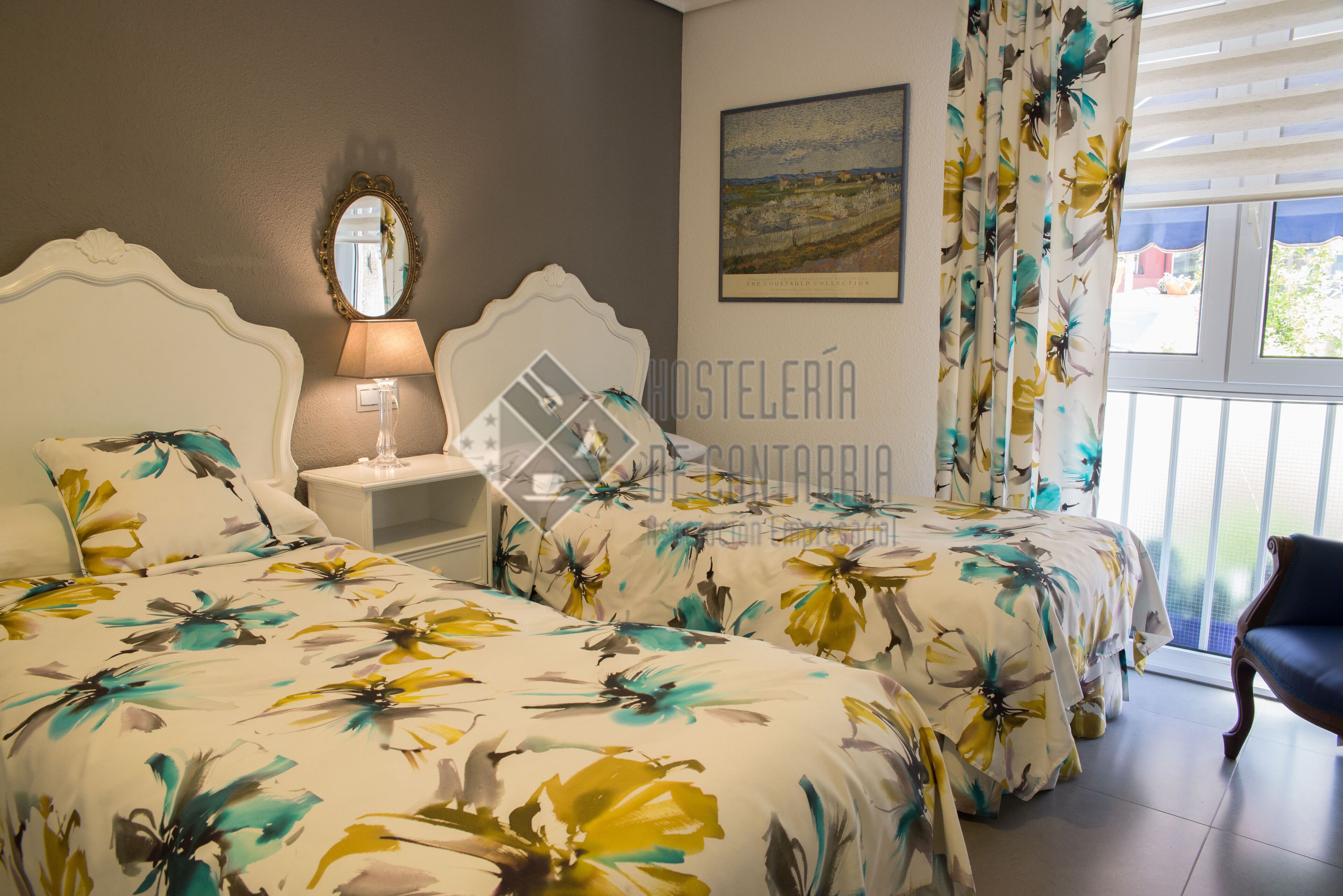 Une chambre avec deux lits, une table de chevet, une lampe, un miroir, une fenêtre avec des rideaux et une chaise.