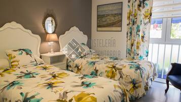 Une chambre avec deux lits, une table de chevet, une lampe, un miroir, une fenêtre avec des rideaux et une chaise.