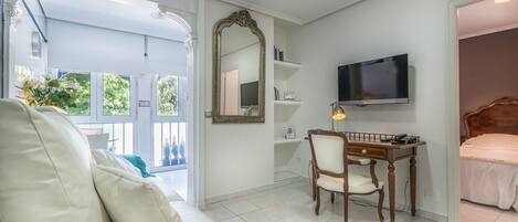 A bedroom with a bed, a desk, a chair, a TV, and a large mirror.