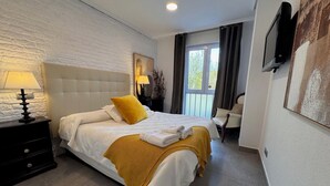 A hotel room with a bed, a nightstand, a chair, and a TV mounted on the wall. - Apartamentos Las Brisas (Santander)