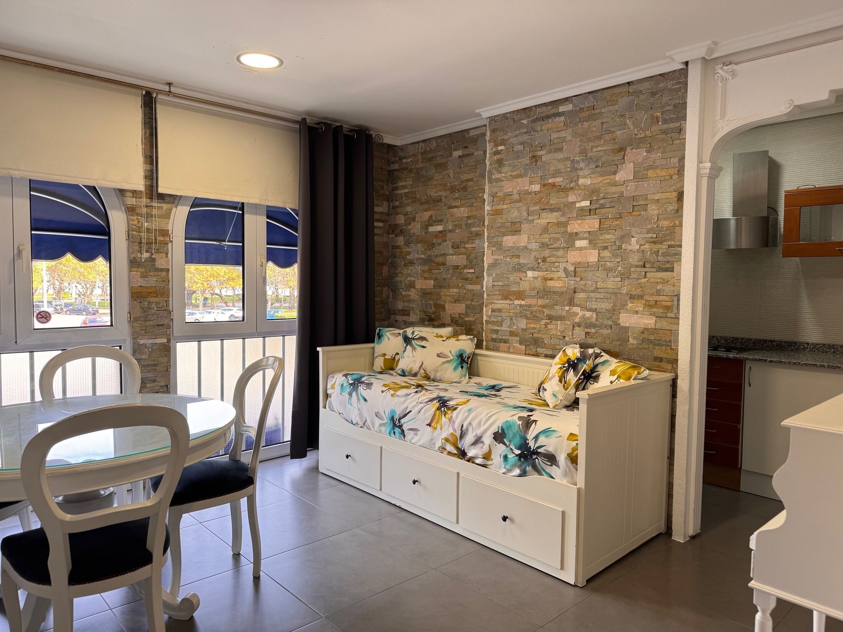 Una habitación con cama, una mesa de comedor con sillas, una zona de cocina y vistas por una ventana.