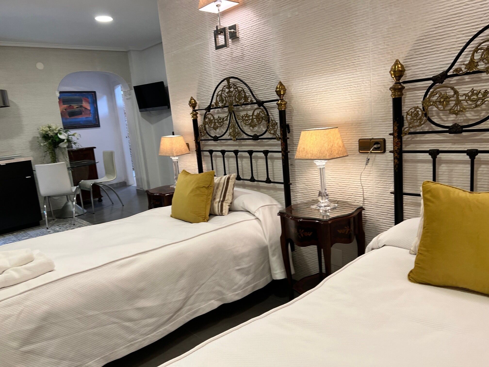 Habitación de hotel con dos camas, un escritorio, una silla, un televisor y una lámpara.