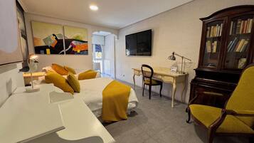 Una habitación con cama, escritorio, silla, estantería y televisor.
