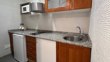 A compact kitchen with a built-in microwave, stainless steel sink, and a dishwasher.