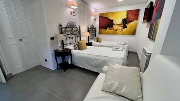 Un dormitorio con una cama, mesitas de noche, una lámpara, un radiador y un cuadro en la pared.
