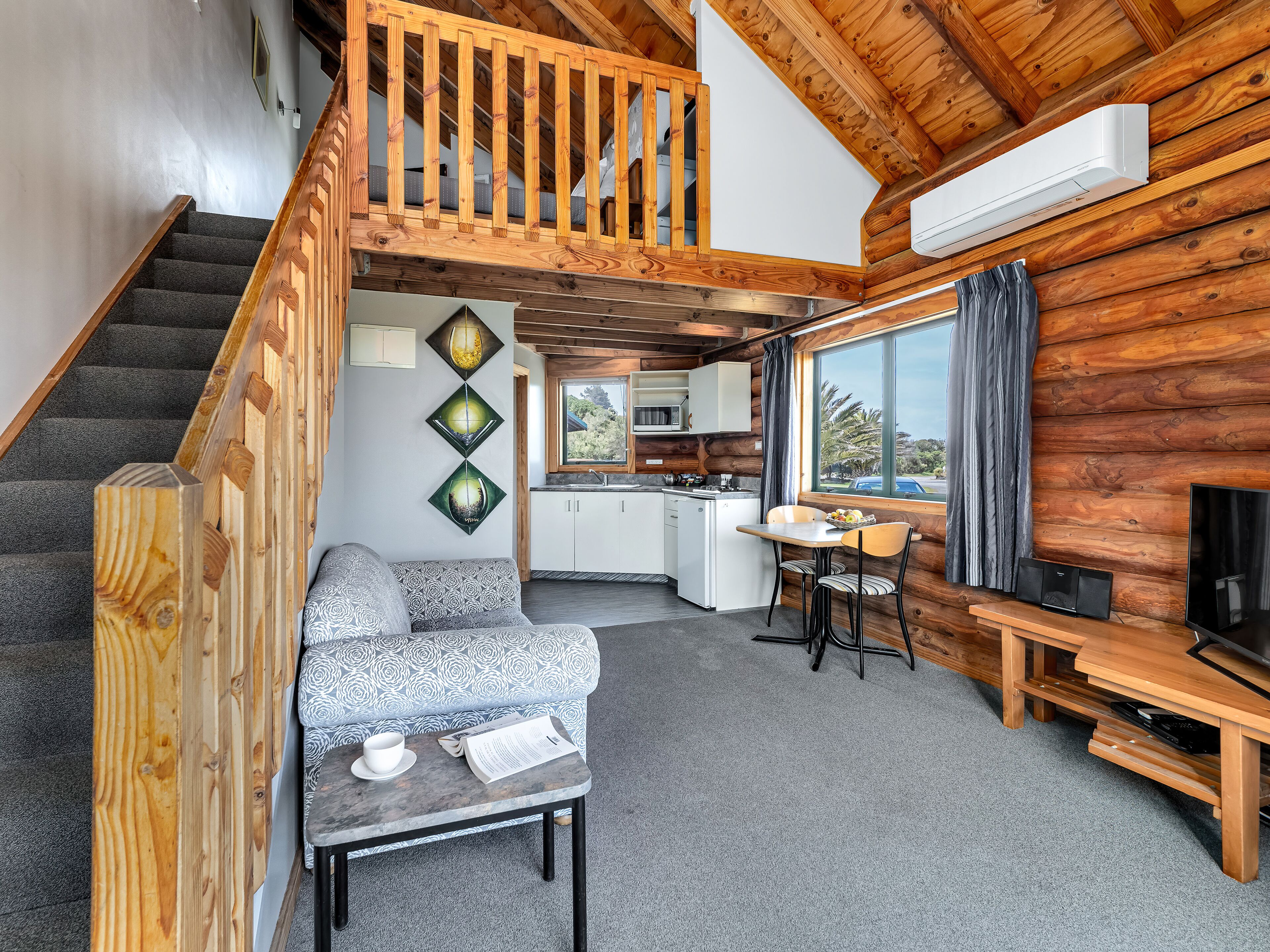 A cozy cabin interior with a staircase, a dining area, and a kitchen.