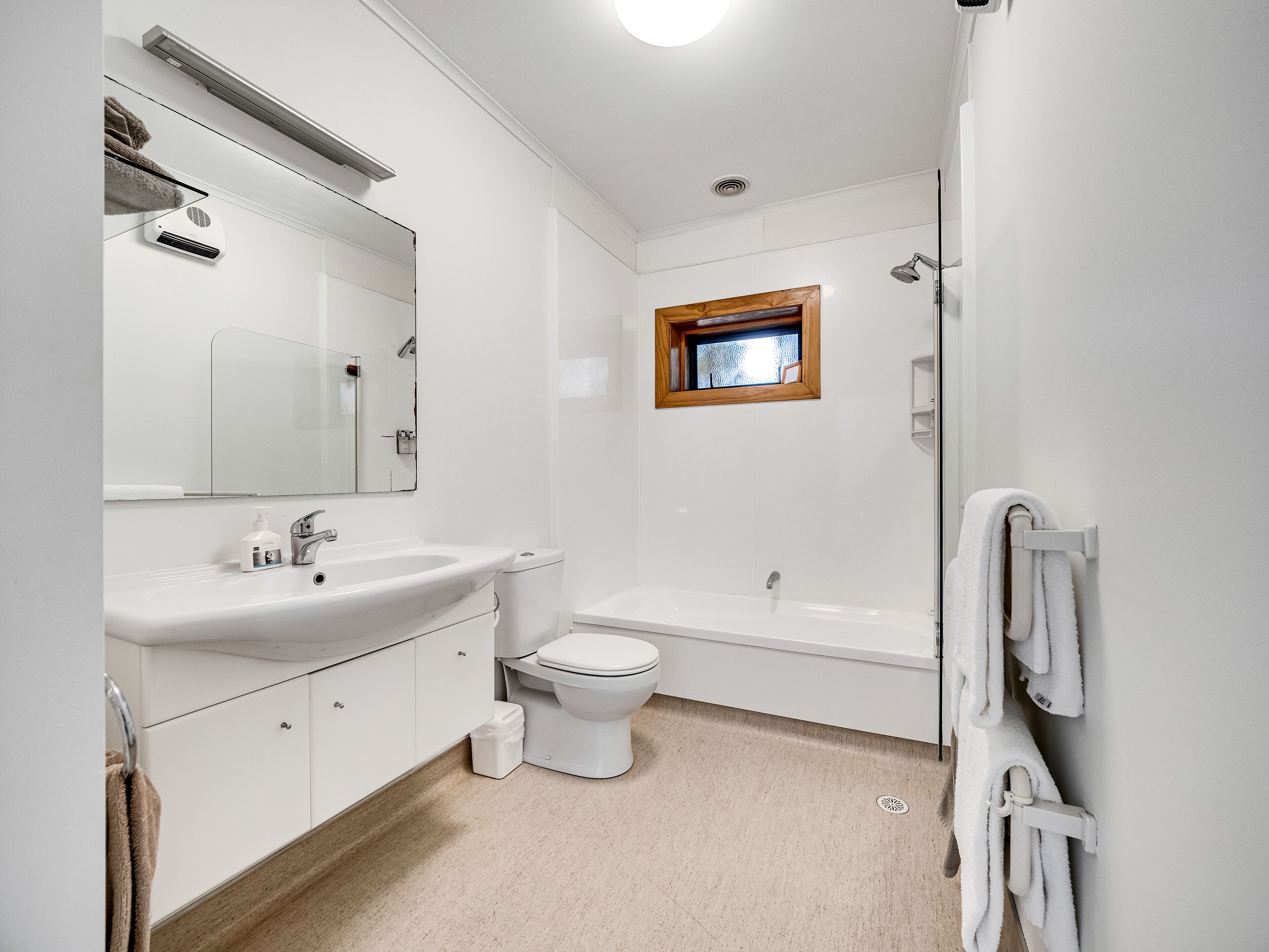 A modern bathroom with a sink, mirror, toilet, and bathtub.
