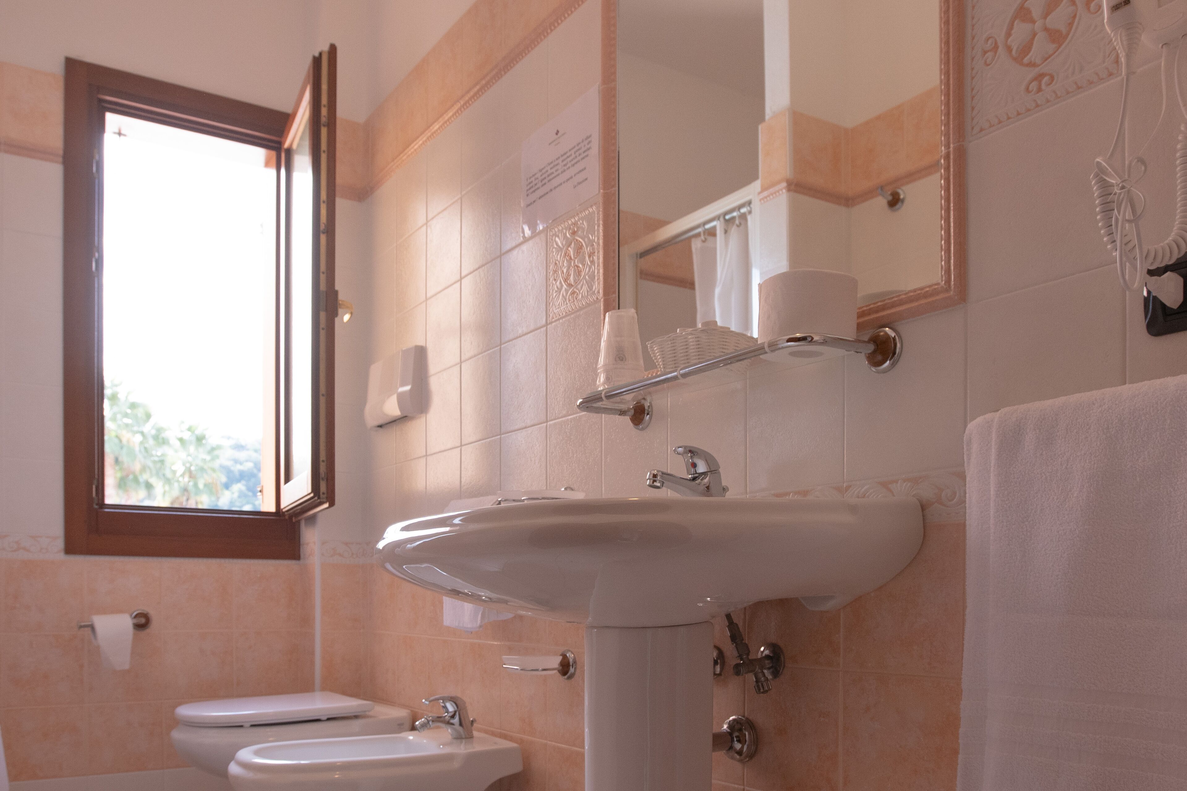 Ein Badezimmer mit Waschbecken, Toilette und Fenster.