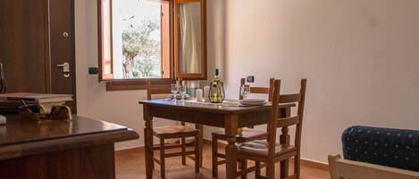 Un comedor con una mesa y sillas de madera, una ventana con cortina abierta y un sofá azul.