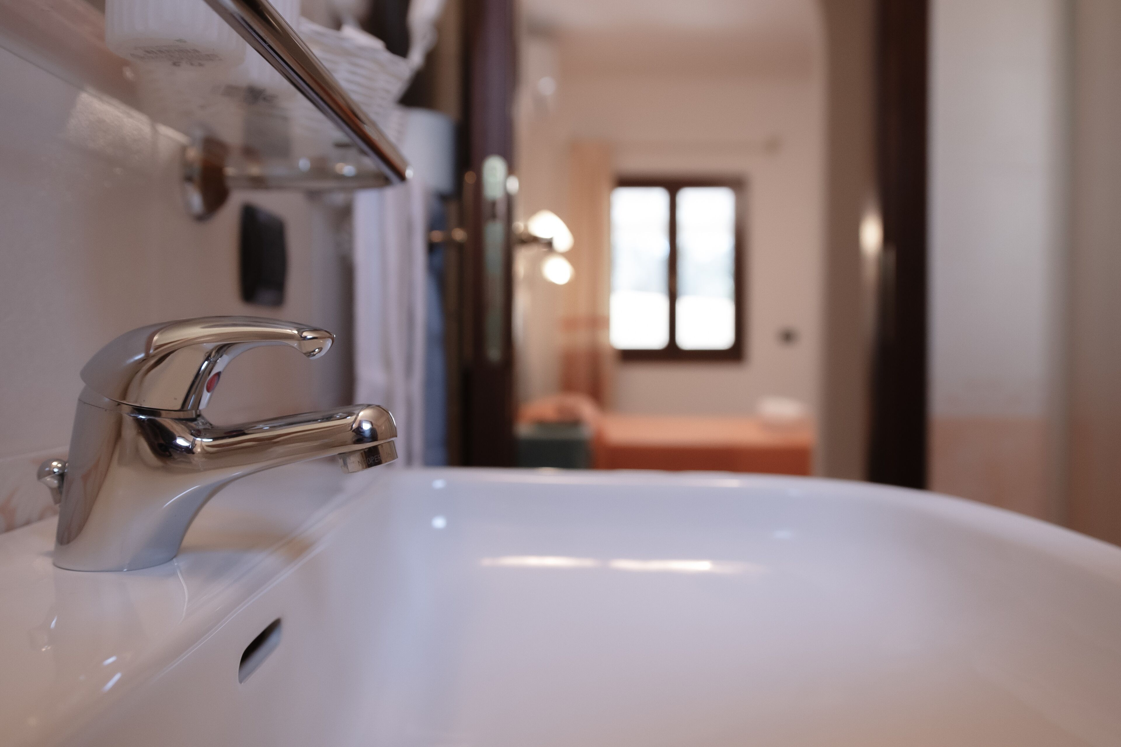 A bathroom with a white sink, chrome faucet, and a mirror above it.
