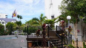 A swimming pool with a no diving sign, surrounded by palm trees and a staircase leading to a deck.