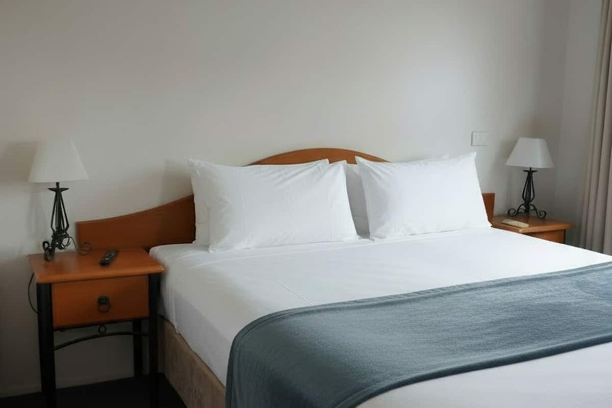 A hotel room with a bed, two bedside tables, and lamps.