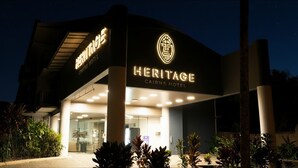 A hotel entrance with a sign reading 'Heritage Cairns Hotel.'
