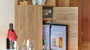 A compact kitchen with wooden cabinetry, a built-in microwave, and a mini-fridge. - Park Hotel (Traben-Trarbach)