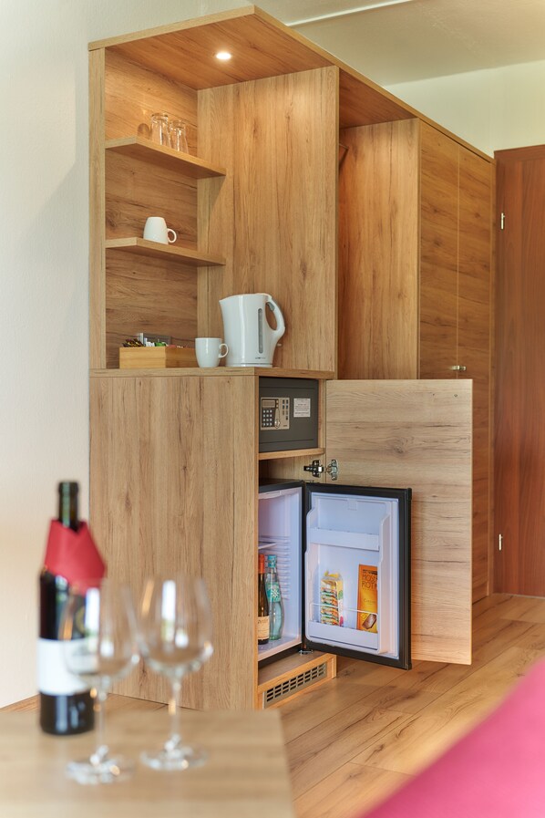 A compact kitchen with wooden cabinetry, a built-in microwave, and a mini-fridge. - Park Hotel (Traben-Trarbach)