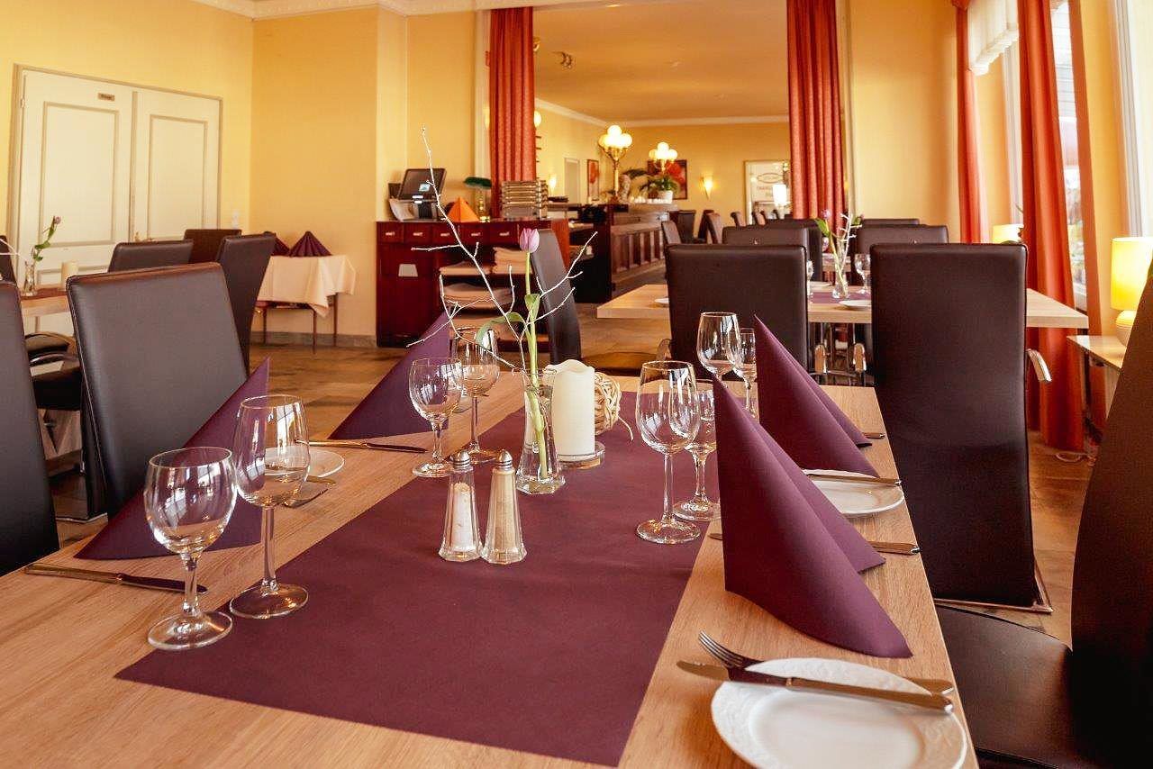 A dining area with tables set for a meal, featuring clear glassware, plates, and napkins.