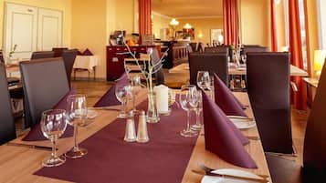A dining area with tables set for a meal, featuring clear glassware, plates, and napkins.