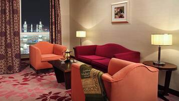 A hotel room with a view of a cityscape at night, featuring two sofas and two lamps.