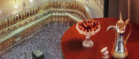 A view of a mosque's courtyard at night with a table featuring a silver pitcher and a bowl of dates.