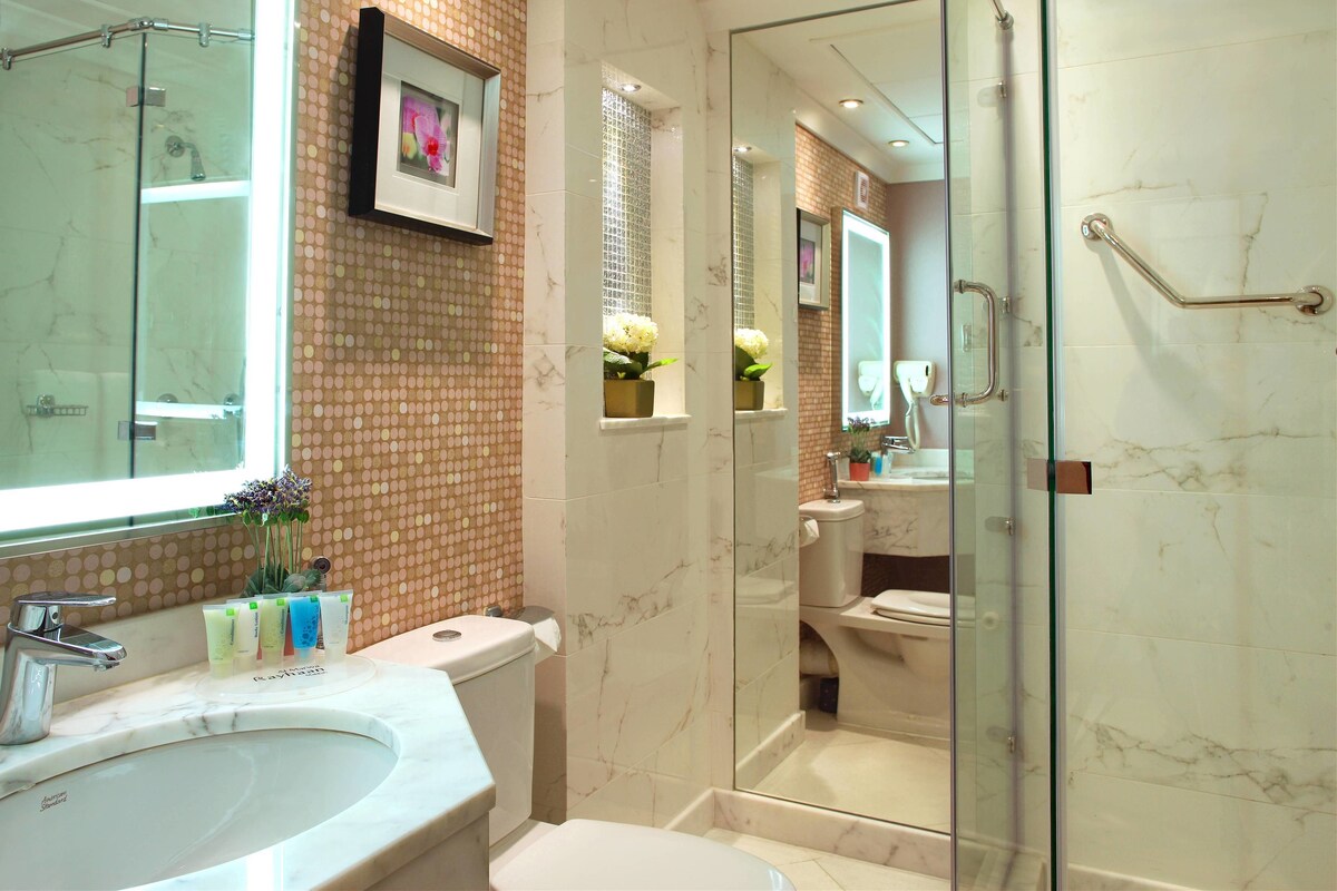 A bathroom with a glass-enclosed shower, a marble sink, and a toilet.