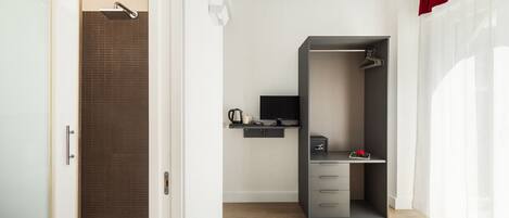 A modern hotel room with a shower, a desk with a computer, and a bed.