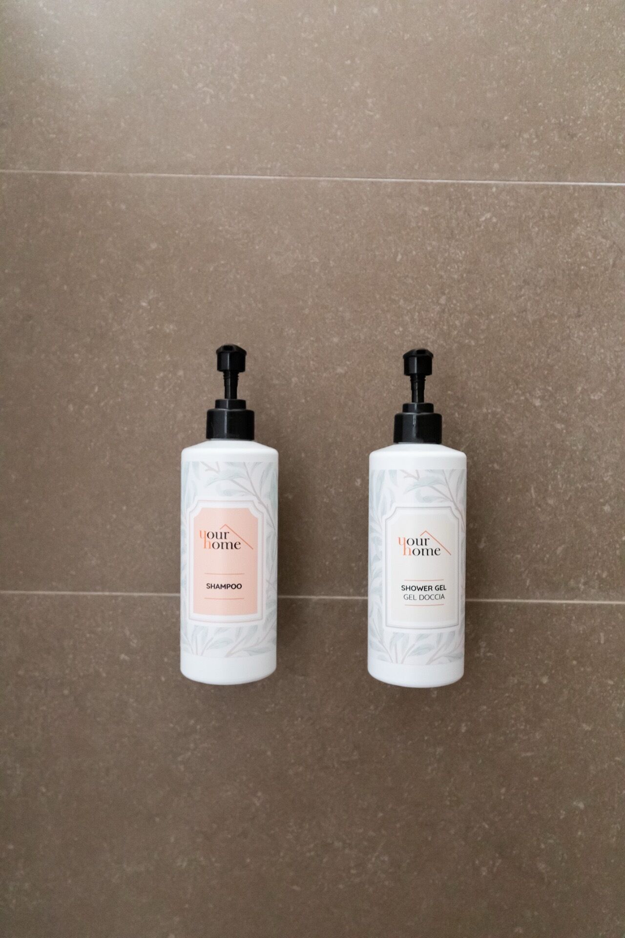 Two white bottles with black pumps on a brown tiled floor.