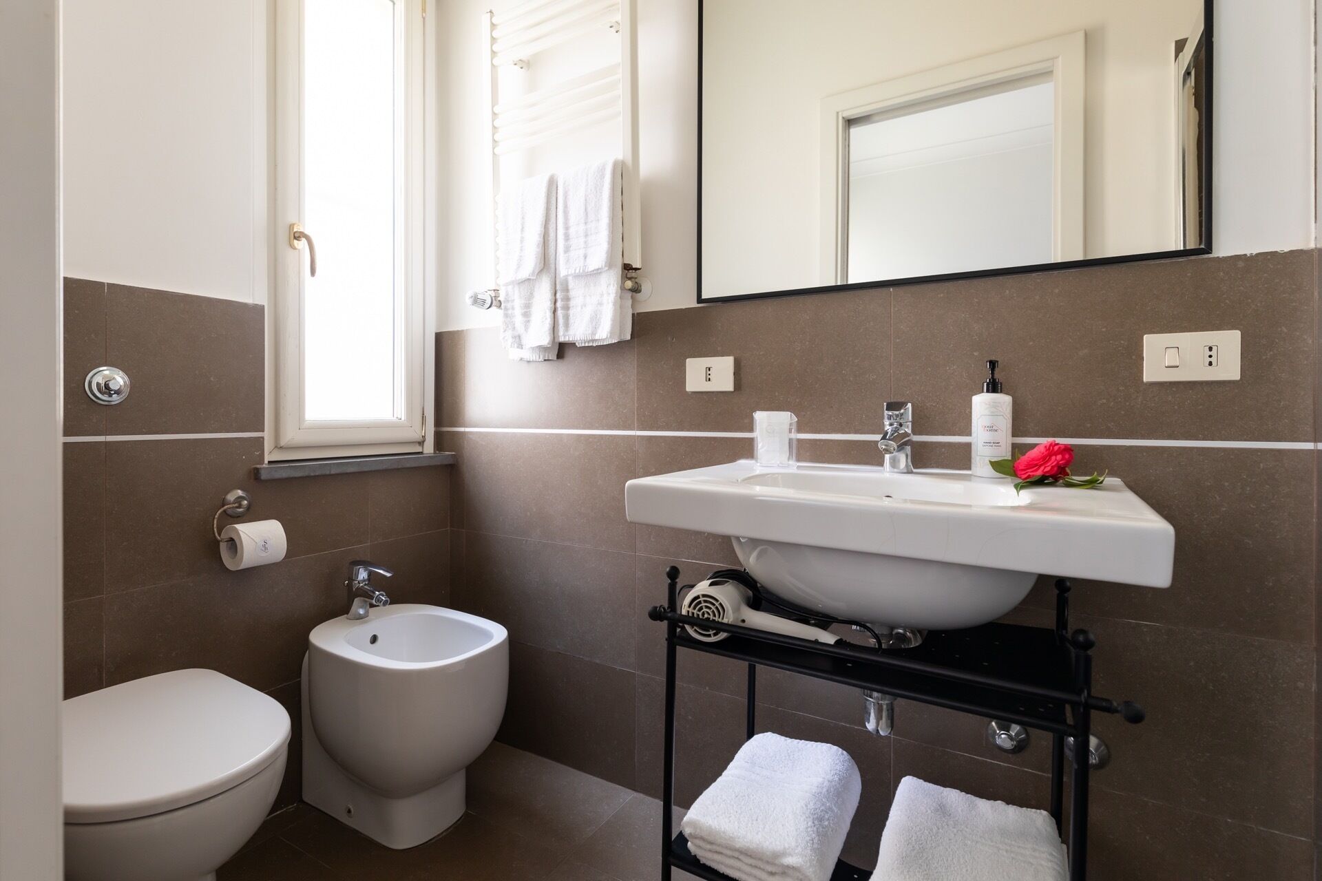 A modern bathroom with a bidet, toilet, sink, and a mirror above the sink.