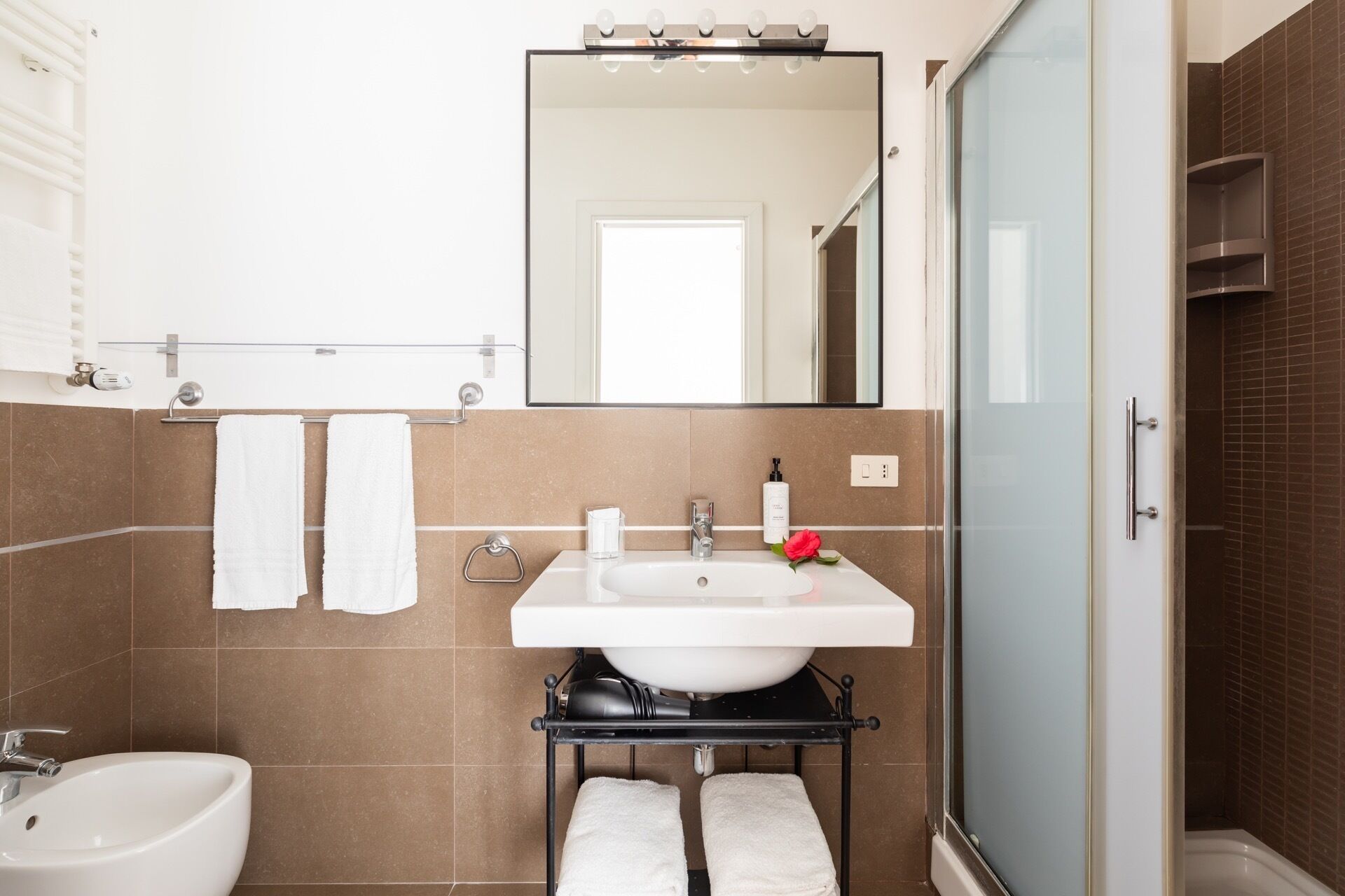A modern bathroom with a white sink, a mirror, and a shower.