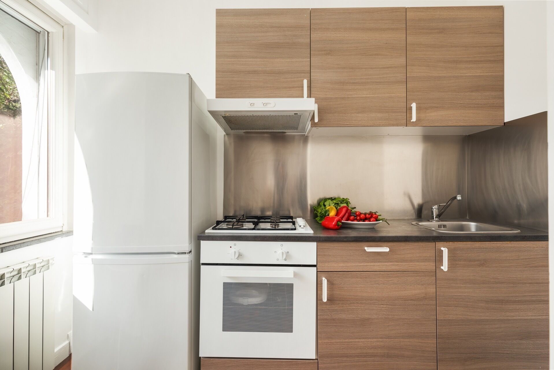 A modern kitchen with white appliances, wooden cabinets, and a stainless steel sink.