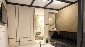 Ein modernes Wohnzimmer mit einer schwarzen Ledersofa, einem Glastisch und einem Holzschrank.