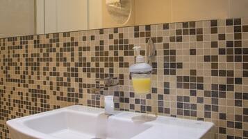 A bathroom with a white sink, a mirror, and a tiled wall.